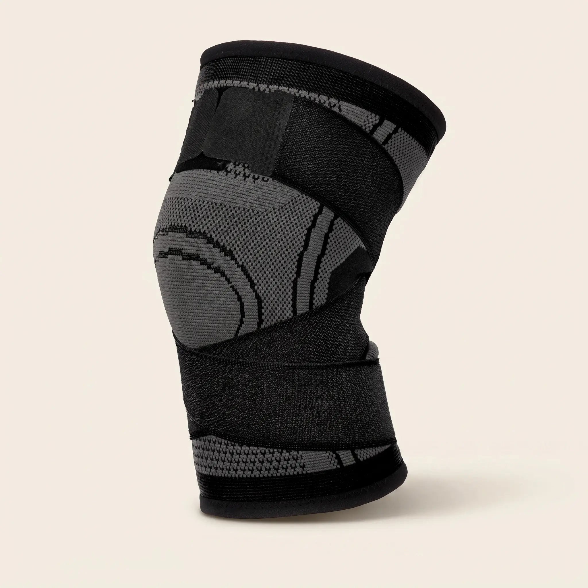 Genouillère de compression Flexnea noire à sangles ajustables, sur fond crème