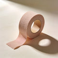 A roll of nude stretch cotton body tape, partially unrolled