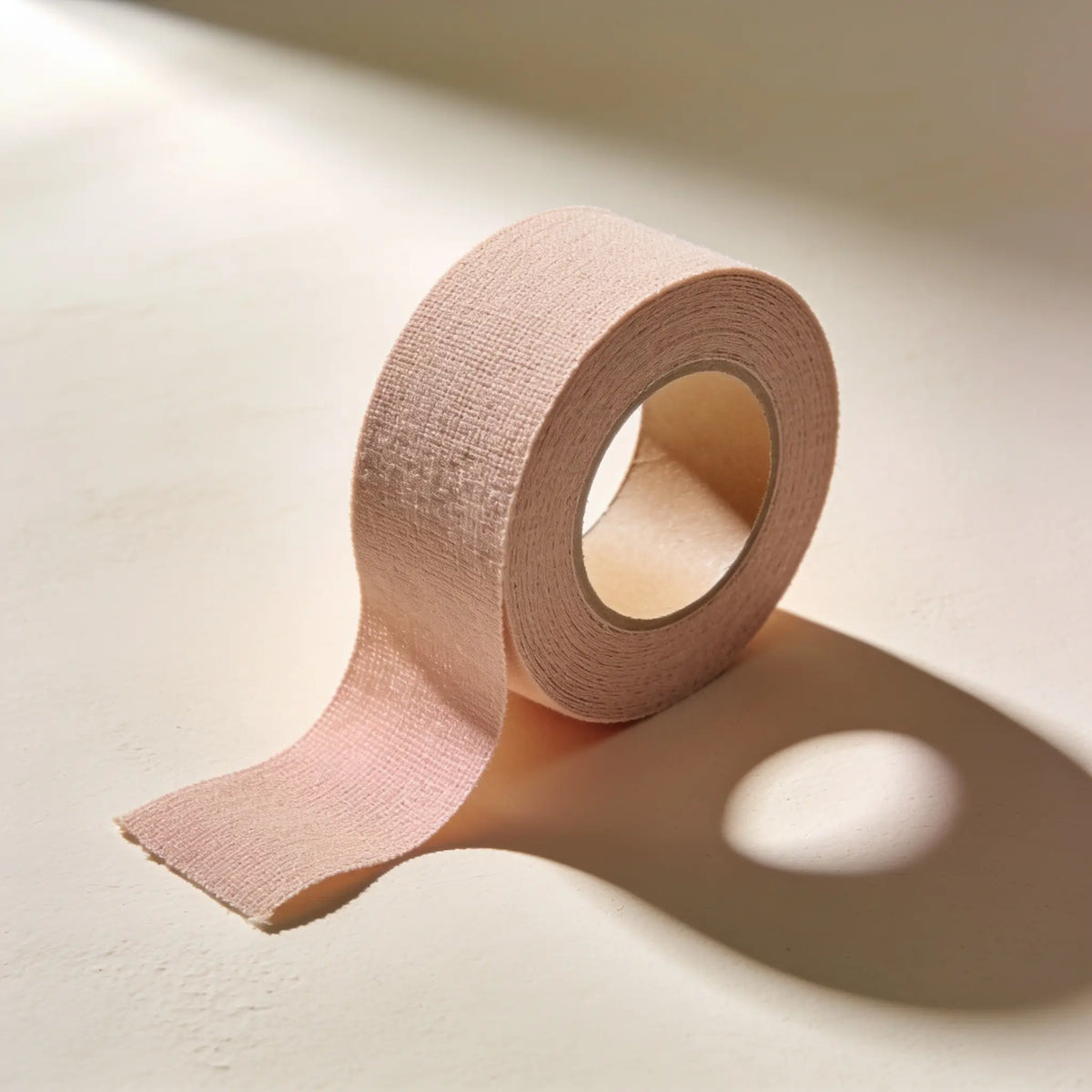 A roll of nude stretch cotton body tape, partially unrolled
