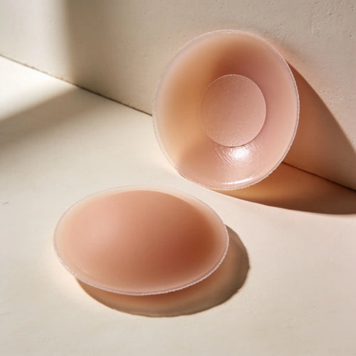 A pair of matte silicone nipple covers with feathered edges