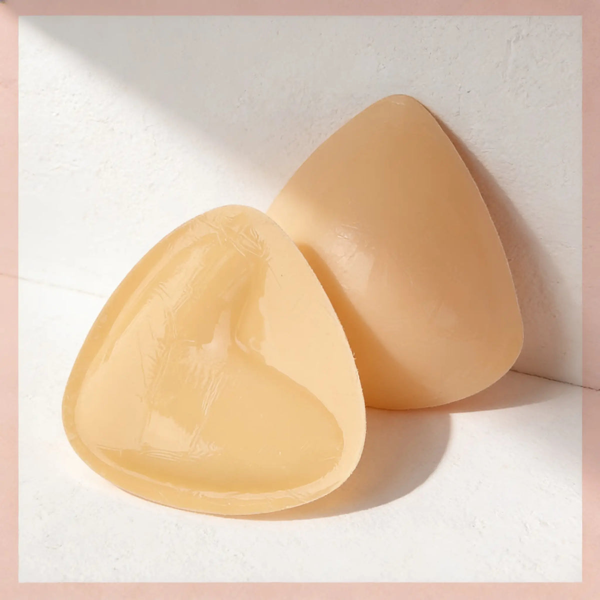 A pair of Sculpt Inserts in nude, one flat and one propped to show the tapered edge